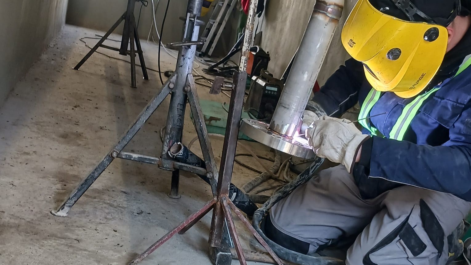 Sudor care sudează o flanșă la un racord lateral pe o țeavă de inox